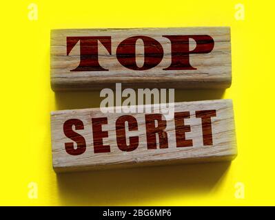 Top Secret words on wooden building blocks isolated on yellow. Marketing or yellow press scandal reveal concept Stock Photo