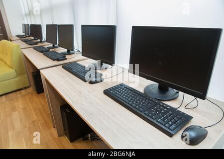 two computers and a desk . Keyboard and mouse . Two computer monitors with a black screen on a desk . Stock Photo