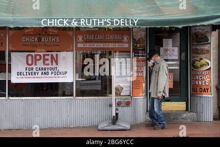 Annapolis, United States. 20th Apr, 2020. Annapolis, Maryland, USA. 20th Apr 2020. A man wears a mask as he looks at a takeout menu in downtown Annapolis, Maryland amid the Coronavirus COVID-19 pandemic on Monday, April 20, 2020. Gov. Larry Hogan, R-MD, recently passed an order that requires all people must wear a face covering before going into any retail establishment.  Photo by Kevin Dietsch/UPI Credit: UPI/Alamy Live News Credit: UPI/Alamy Live News Stock Photo