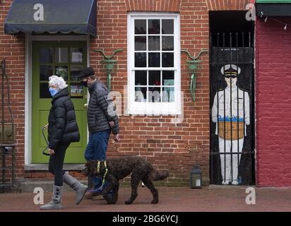Annapolis, United States. 20th Apr, 2020. People wear masks as they walk a dog on Main Street in downtown Annapolis, Maryland amid the Coronavirus COVID-19 pandemic on Monday, April 20, 2020. Gov. Larry Hogan, R-MD, recently passed an order that requires all people must wear a face covering before going into any retail establishment.  Photo by Kevin Dietsch/UPI Stock Photo