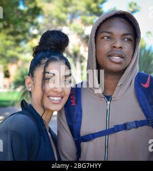 A lovely young woman and man of color, enjoy campus life as students with hoodie and trendy up-do hairstyle and smiles at the U of A in Tucson, AZ Stock Photo