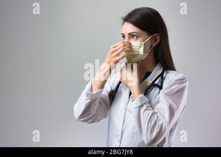 Woman healthcare professional demonstrating proper donning of mask for protection from coronavirus. Up close female healthcare worker putting on safet Stock Photo