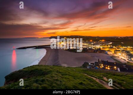 West Bay, Dorset, UK.  20th April 2020.  UK Weather.  The clouds glow red shorty after sunset at the seaside resort of West Bay in Dorset with the settled weather set to continue this week with rising temperatures.  Picture Credit: Graham Hunt/Alamy Live News Stock Photo