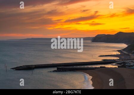 West Bay, Dorset, UK.  20th April 2020.  UK Weather.  The sky glows orange shorty after sunset at the seaside resort of West Bay in Dorset with the settled weather set to continue this week with rising temperatures.  Picture Credit: Graham Hunt/Alamy Live News Stock Photo