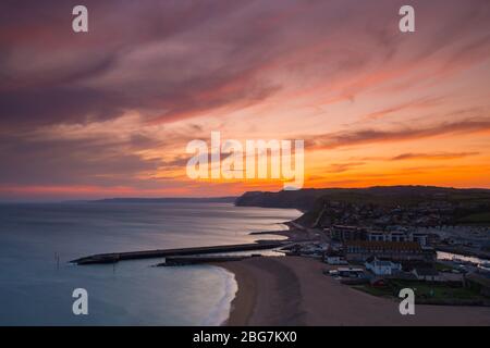 West Bay, Dorset, UK.  20th April 2020.  UK Weather.  The clouds glow red shorty after sunset at the seaside resort of West Bay in Dorset with the settled weather set to continue this week with rising temperatures.  Picture Credit: Graham Hunt/Alamy Live News Stock Photo