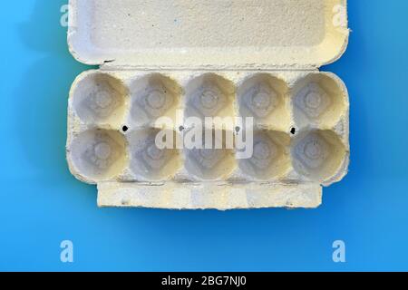 Empty cardboard tray top view. Egg tray on a blue background. Paper gray tray without eggs. Stock Photo