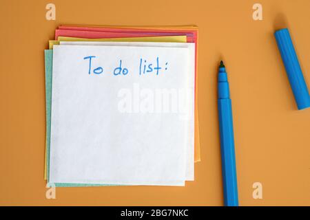 Reminder sticky note and blue felt-tip pen, inscription to do list. White sheet of paper planning action for the day, month. Notation paper. Stock Photo