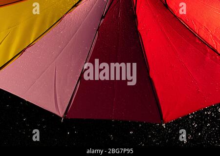 A multi colored rainbow umbrella with rain running down its sides Stock Photo