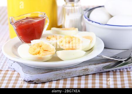 Boiled eggs on wooden board on tablecloth Stock Photo