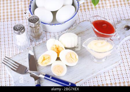 Boiled eggs on wooden board on tablecloth Stock Photo