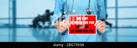 COVID-19 Social distancing quote medical nurse promoting staying at home to help workers. Coronavirus doctor holding sign in hospital background. Panoramic corona virus sign banner with text title. Stock Photo