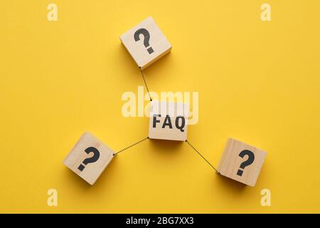 Concept FAQ - abstract signs on wooden cubes with yellow background. Close up. Stock Photo