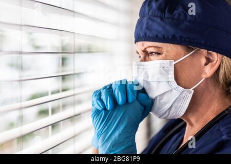 Prayerful Stressed Female Doctor or Nurse On Break At Window Wearing ...