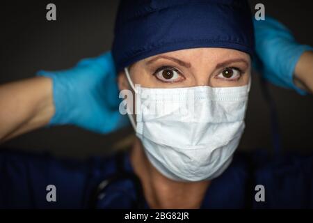 Female Doctor or Nurse Wearing Surgical Gloves Putting On Medical Face Mask. Stock Photo