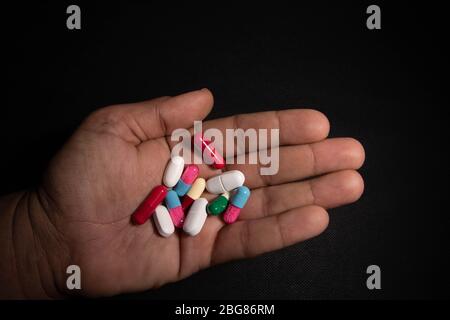 A man holds many different pills in his hand. Medicine concept Stock Photo