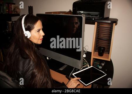 Woman working in office in front of computer using hearing aid and headband technology in Mexico City Stock Photo
