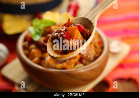Chili Corn Carne - traditional mexican food, in wooden bowl, on napkin, on wooden background Stock Photo