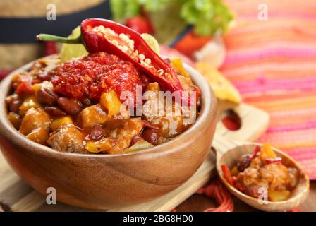 Chili Corn Carne - traditional mexican food, in wooden bowl, on napkin, on wooden background Stock Photo