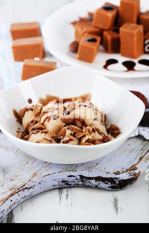 Many toffee on plate and in bowl on napkin on board close-up Stock Photo