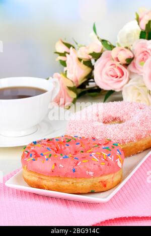 Sweet donuts with cup of tea on table on light background Stock Photo