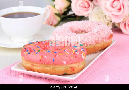 Sweet donuts with cup of tea on table on light background Stock Photo