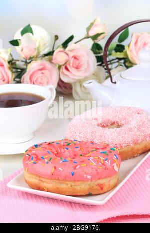 Sweet donuts with cup of tea on table on light background Stock Photo