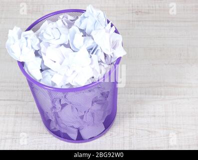 Recycle bin filled with crumpled papers, on floor Stock Photo