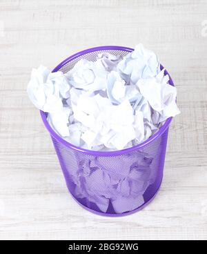 Recycle bin filled with crumpled papers, on floor Stock Photo