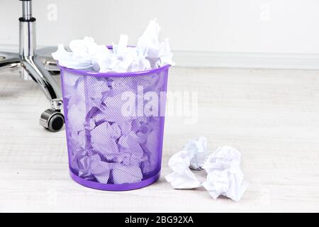 Recycle bin filled with crumpled papers, on floor Stock Photo