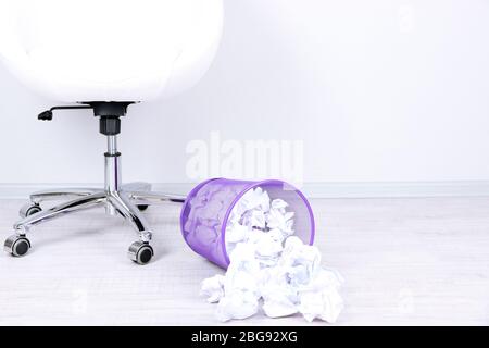Recycle bin filled with crumpled papers, on floor Stock Photo