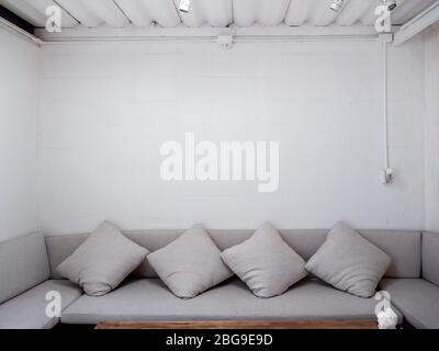 Minimalist style living room with grey sofa with throw pillows on white wall background with copy space. Stock Photo