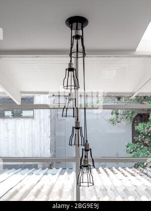 Modern black metal ceiling light with light bulbs hanging from white ceiling, room decoration retro style, vertical style. Stock Photo