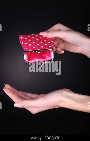 Female hand holding pink purse on black background Stock Photo