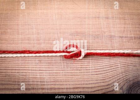 OVERHAND BOW knot. Example of training and information. Red and white cord on a wooden background Stock Photo