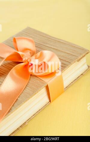 Book wrapped with color ribbon, on wooden background Stock Photo - Alamy