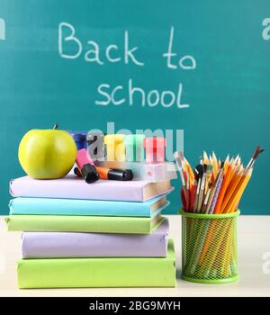 School supplies on table on blackboard background Stock Photo