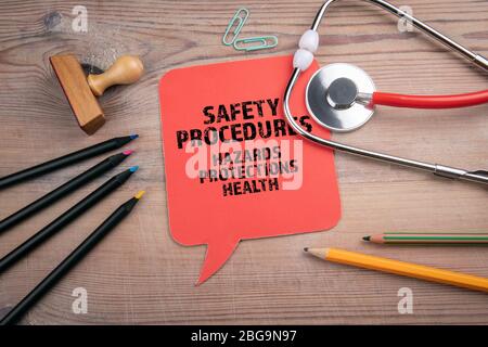 Safety Procedures. Hazards, protections and health concept. Red speech bubble and stethoscope on a wooden table Stock Photo