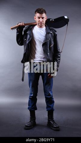 Young musician with guitar on dark color background Stock Photo