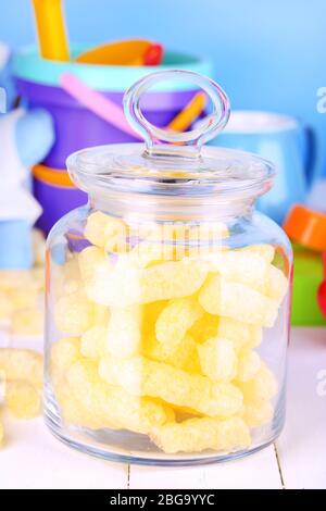 Air corn sticks in glass bank on wooden table surrounded by toys Stock Photo