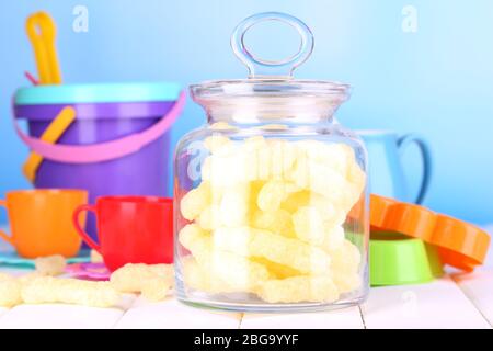 Air corn sticks in glass bank on wooden table surrounded by toys Stock Photo
