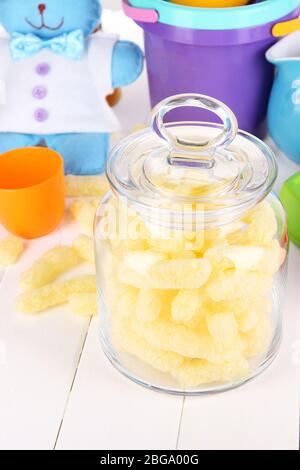 Air corn sticks in glass bank on wooden table surrounded by toys Stock Photo