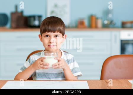 Little boy drinking milk in kitchen Stock Photo