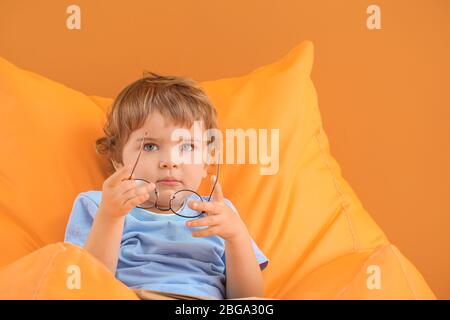 Cute little boy with eyeglasses on color background Stock Photo