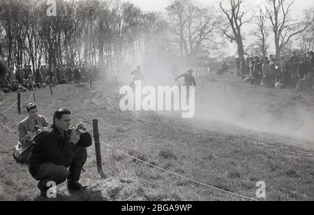 1960s, historical, spectators standing on a hilly ridge, watching an off-road motorcycle scramble race, a sport which later became commonly known as motorcross racing. The first ever official scramble was held in Camberley, Surrey, in 1924. Post-WW2 the sport expanded as motorbikes became lighter and faster. Stock Photo