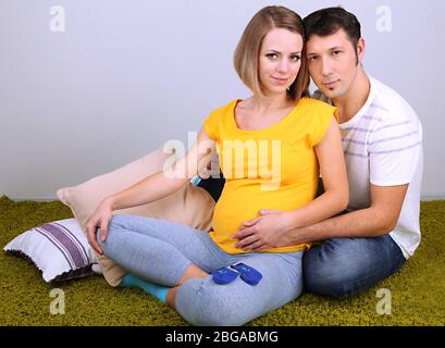 Young pregnant woman with her husband sitting on floor at home Stock Photo