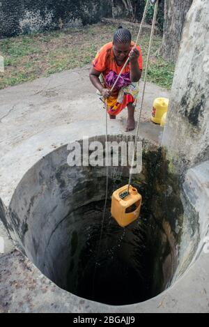 Lamu, Kenya - December 15, 2016: Black African woman pulling water from well in Lamu town Stock Photo