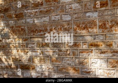 Old preserved 19th Century brown limestone building wall texture background with tuckpointing mortar joints, showing light filtered tree shadows Stock Photo