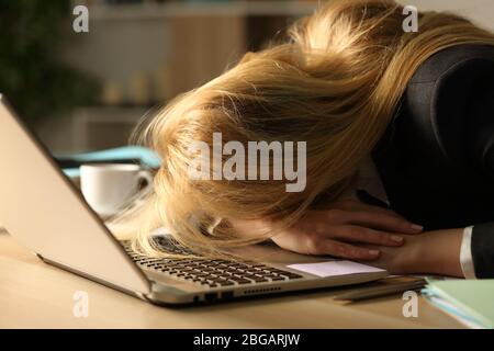Close up of overworked entrepreneur woman sleeping over desk at night at home office Stock Photo