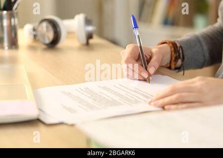 Close up of student girl hands signing contract on a desk at home Stock Photo