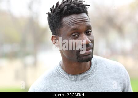 Suspicious black man looking camera standing outdoors in a park Stock Photo